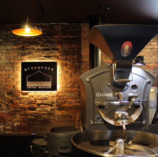 Kahvinpaahdin ja Stockfors Coffee Roasters -kyltti tiiliseinällä paahtimolla